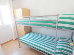 a bunk bed with green and white striped pillows on it at Colibri II-1 in Roses