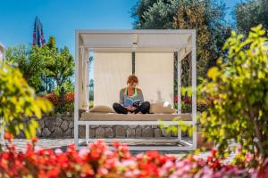 a woman sitting on a bed in a gazebo at Maison Montechiaro in Vico Equense