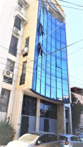 Central Luxury Apartment في تيرانا: مبنى طويل وبه نوافذ من الزجاج الأزرق