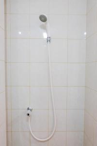 a shower with a hose in a white tiled bathroom at Comfortable and Fully Furnished Studio at Poris 88 Apartment By Travelio in Tangerang