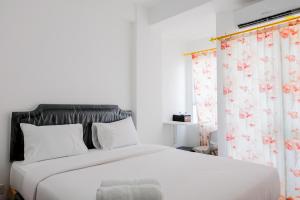 a bedroom with a large white bed with floral curtains at Comfortable and Fully Furnished Studio at Poris 88 Apartment By Travelio in Tangerang