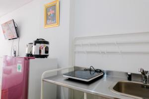 a kitchen with a sink and a counter with a tray on it at Comfortable and Fully Furnished Studio at Poris 88 Apartment By Travelio in Tangerang