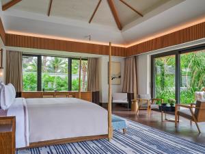 a bedroom with a large bed and a living room at Capella Tufu Bay, Hainan in Sanya