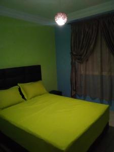 a bedroom with a green bed with a window at Appartement meublé sécurisé in Agadir