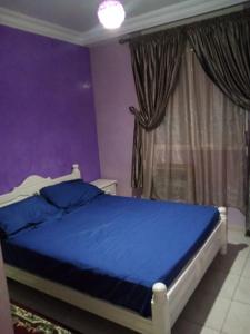 a bedroom with a blue bed and a purple wall at Appartement meublé sécurisé in Agadir
