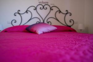 a pink bed with a metal headboard and a pink pillow at Le casette di Frà al Bondì in Santa Severa