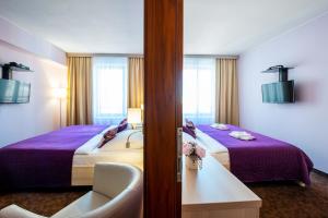 um quarto de hotel com duas camas com lençóis roxos em Hotel Mlynska em Uherské Hradiště