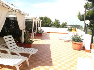 a patio with white chairs and umbrellas at Residence Maresol in Vieste