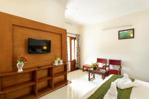 Habitación de hotel con cama y TV en Le Celestium en Munnar