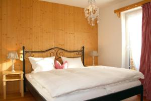 um quarto com uma cama com lençóis brancos e um lustre em Gästehaus Alpin em Oberstdorf