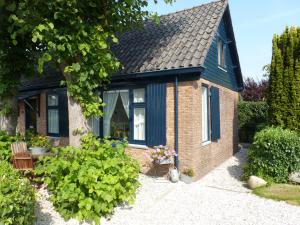 uma pequena casa de tijolos com um telhado preto em Huis De Roos em De Kwakel