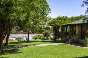 
a park with trees and grass and a house at Tzamenkomst River Lodge in Colesberg
