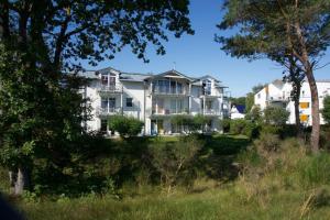 a large white house on a hill with trees at Am Strand in Juliusruh