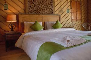 a bedroom with a large white bed with green pillows at SAMA Ras Al Jinz Ecolodge in Sur +18 photos