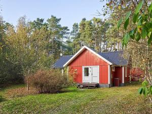 a red shed with a white door in a yard at 6 person holiday home in Aakirkeby in Vester Sømarken