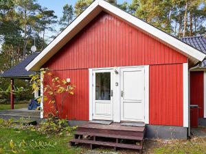 a red shed with a white door and a porch at 6 person holiday home in Aakirkeby in Vester Sømarken
