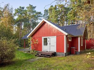 a red shed with a white door in a yard at 6 person holiday home in Aakirkeby in Vester Sømarken