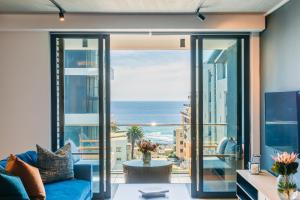 a living room with a blue couch and a view of the ocean at Latitude Aparthotel by Totalstay in Cape Town