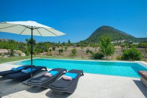 una piscina con 2 tumbonas y una sombrilla en Owl Booking Villa La Rafal - Luxury Retreat with Mountain Views en El Port