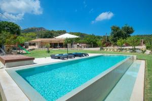 uma piscina com água azul num quintal em Owl Booking Villa La Rafal - Luxury Retreat with Mountain Views em El Port