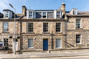 an old stone building with a blue door at Pilmour Place - 30 Seconds to the Old Course! in St Andrews