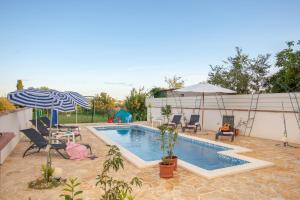 a swimming pool with chairs and an umbrella at Villa Pax in Marčana