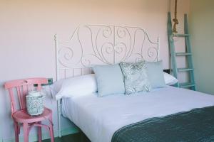 1 dormitorio con cama blanca y cabecero rosa en ALTAIR Turismo Rural, en Béjar