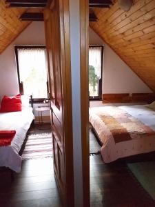 a attic bedroom with two beds and two windows at Planinska kuća MAK in Jahorina