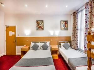 a hotel room with two beds and two windows at OYO London Guest House in London