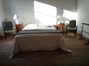 a bedroom with a bed with two chairs and a table at Le Logis de Miserè in Celles-sur-Belle