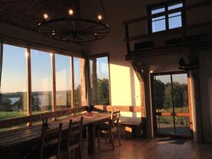 - une salle à manger avec une table, des chaises et des fenêtres dans l'établissement Spichlerz Nad Jeziorem Dadaj Mazury, à Biskupiec