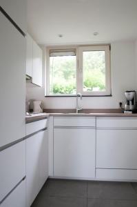 a white kitchen with a sink and two windows at Zonnedauw in Kamperland