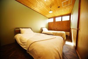 1 dormitorio con 2 camas y ventana en HAKUBA LODGE OMUSUBI, en Otari