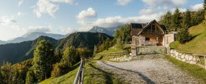 a house on a hill with mountains in the background at Eco Chalet AstraMONTANA in Tolmin