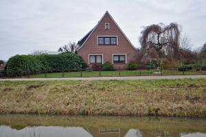 a house on the side of a road next to a river at Ferienwohnung An der Wieke, 65295 in Moormerland