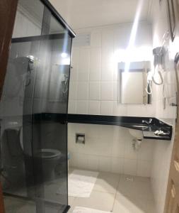 a bathroom with a shower and a toilet at Thanharu Praia Hotel in Anchieta