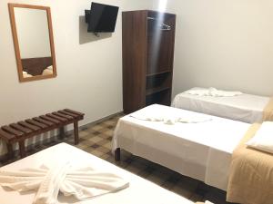 una camera d'albergo con due letti e uno specchio di Thanharu Praia Hotel a Anchieta