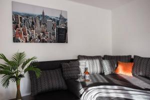 Csigaház Apartman في بيتْش: غرفة معيشة مع أريكة سوداء مع صورة لمدينة