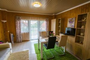a living room with a desk with chairs and a television at Joli Guesthouse in Ordacsehi