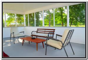 une terrasse couverte avec des chaises, une table et un banc dans l'établissement The Cardinal Inn, à Luray