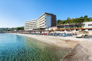 una playa con sillas y sombrillas junto al agua en Ammon Zeus Luxury Beach Hotel en Kallithea Halkidikis