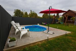 uma pequena piscina com duas cadeiras e um guarda-sol em Joli Guesthouse em Ordacsehi