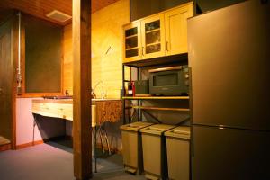 eine Küche mit Kühlschrank und Spüle in der Unterkunft HAKUBA LODGE OMUSUBI in Otari