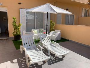 2 sillas blancas y una sombrilla en el patio en BRAND NEW APARTMENT, en Tarifa