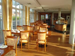 un restaurante con mesas y sillas de madera y ventanas en Vier Jahreszeiten Bensersiel en Bensersiel