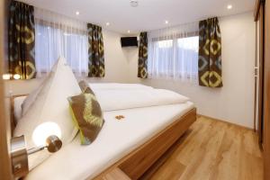 a large white bed in a room with windows at Appartement Moni in Sankt Gallenkirch