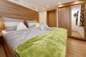 a bedroom with a large bed with a green blanket on it at Appartement Moni in Sankt Gallenkirch