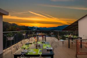 ein Restaurant mit Tischen und Stühlen auf einem Balkon mit Blick auf den Sonnenuntergang in der Unterkunft Sterling Thekkady in Thekkady