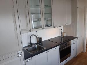 a kitchen with white cabinets and a sink at feriehus ved sjøen in Tomrefjord