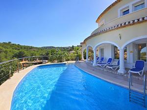 a swimming pool with blue chairs next to a house at Villa Jarmila in Jávea